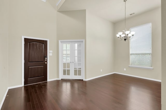 foyer featuring a towering ceiling, dark wood-type flooring, and a chandelier