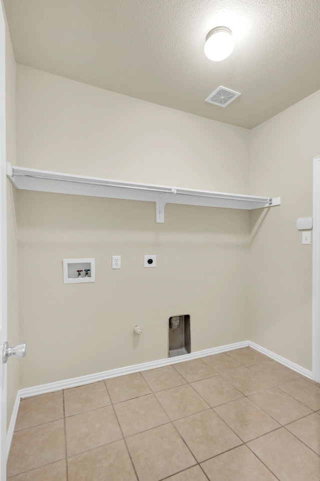 clothes washing area with hookup for an electric dryer, gas dryer hookup, light tile patterned floors, a textured ceiling, and washer hookup