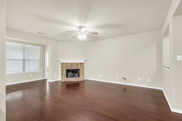 unfurnished living room featuring ceiling fan, a stone fireplace, and dark hardwood / wood-style flooring