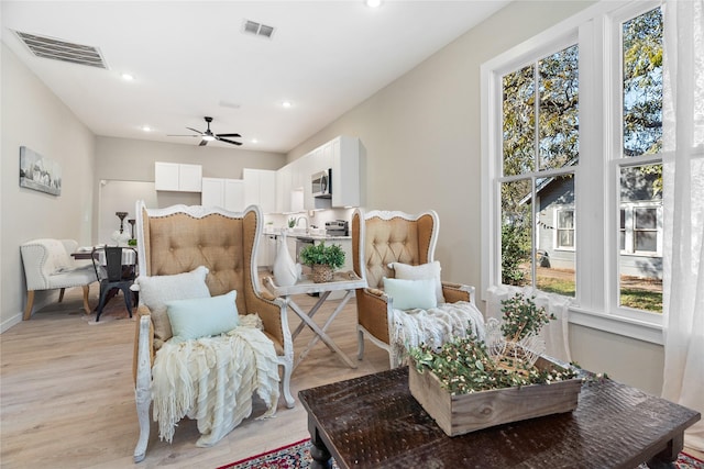 sitting room with ceiling fan and light wood-type flooring