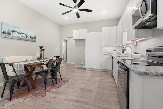 kitchen with sink, light hardwood / wood-style flooring, white cabinetry, stainless steel appliances, and light stone counters