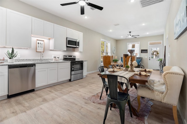 kitchen featuring white cabinetry, sink, stainless steel appliances, and light hardwood / wood-style floors