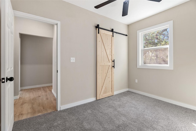 unfurnished bedroom with a barn door, carpet floors, and ceiling fan