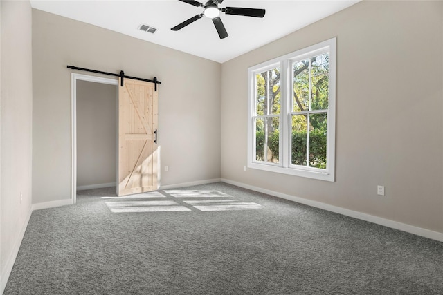 spare room featuring a barn door, carpet floors, and ceiling fan