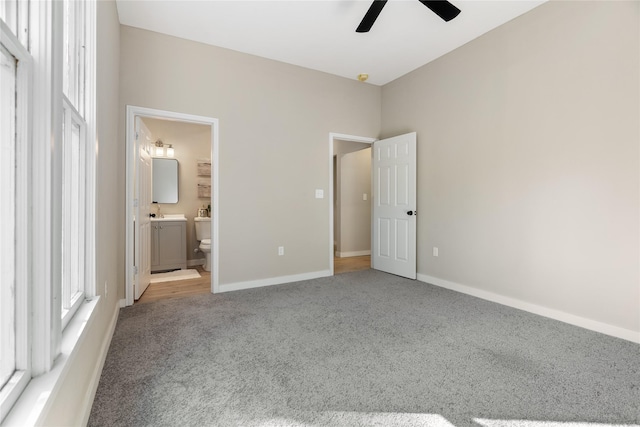 unfurnished bedroom featuring sink, light colored carpet, ceiling fan, and ensuite bath