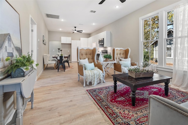 living room with light hardwood / wood-style flooring and ceiling fan