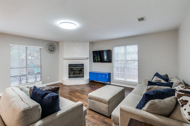 living room with a brick fireplace and dark hardwood / wood-style floors