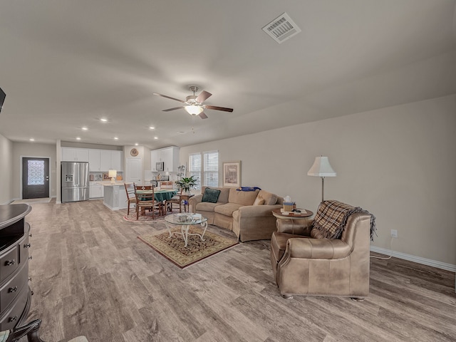 living room with light wood-type flooring and ceiling fan