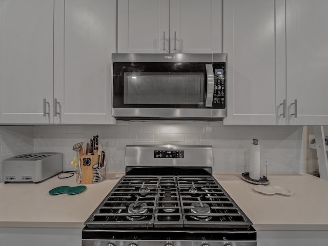 kitchen with tasteful backsplash, appliances with stainless steel finishes, and white cabinets