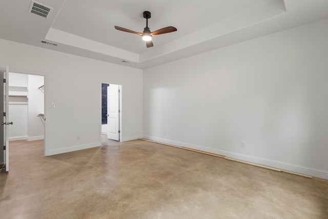 empty room featuring ceiling fan and a raised ceiling