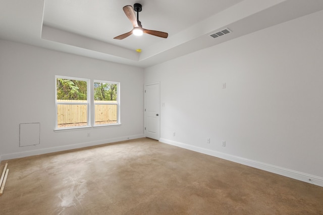 carpeted spare room featuring a tray ceiling and ceiling fan