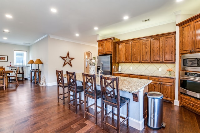 kitchen featuring an island with sink, dark wood-type flooring, and appliances with stainless steel finishes