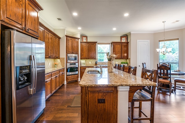 kitchen with a center island with sink, appliances with stainless steel finishes, decorative light fixtures, dark hardwood / wood-style floors, and plenty of natural light