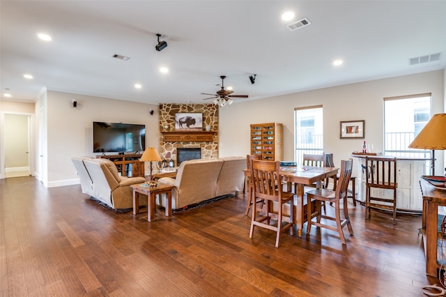 dining space with ceiling fan, dark hardwood / wood-style floors, and a fireplace