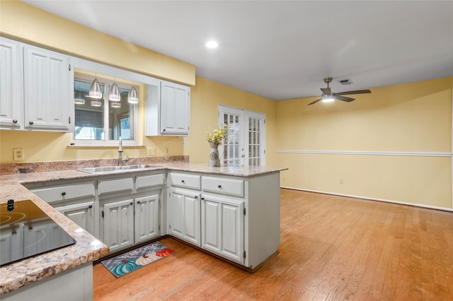 kitchen featuring white cabinets, kitchen peninsula, light hardwood / wood-style floors, and sink