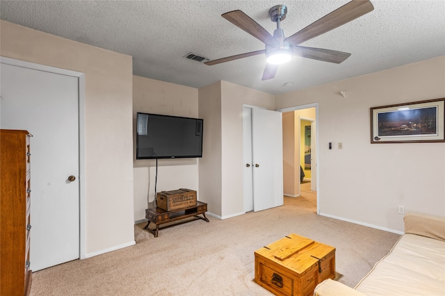 carpeted living room with ceiling fan and a textured ceiling