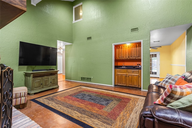 living room with ceiling fan, a towering ceiling, and sink