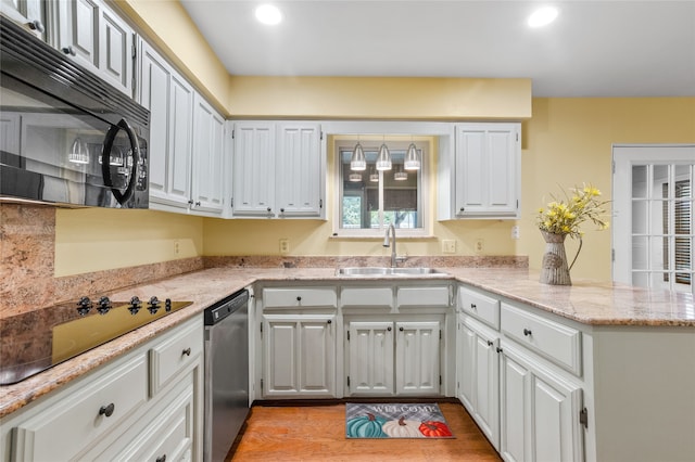 kitchen with light hardwood / wood-style floors, white cabinetry, sink, black appliances, and kitchen peninsula