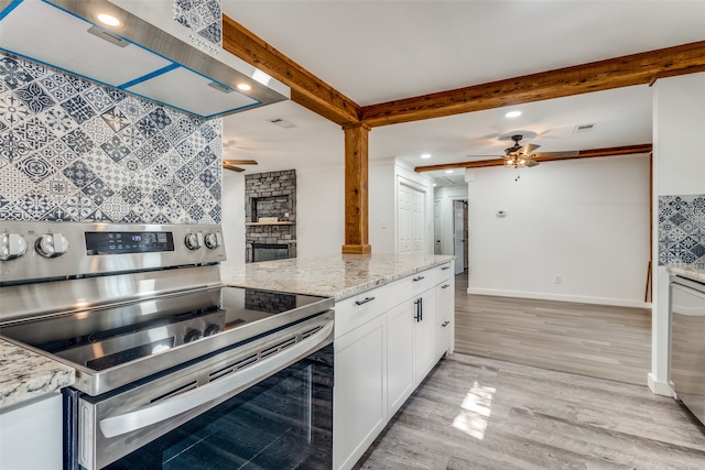 kitchen featuring stainless steel electric range, light stone counters, white cabinets, wall chimney exhaust hood, and light hardwood / wood-style flooring