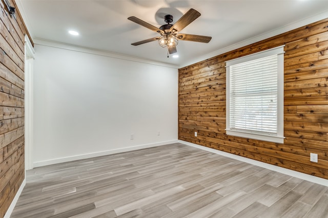 unfurnished room with ornamental molding, light hardwood / wood-style floors, wood walls, and ceiling fan