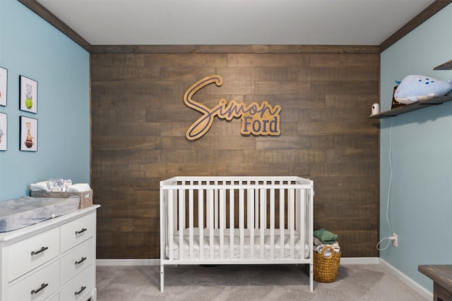 carpeted bedroom featuring ornamental molding, a nursery area, and wood walls