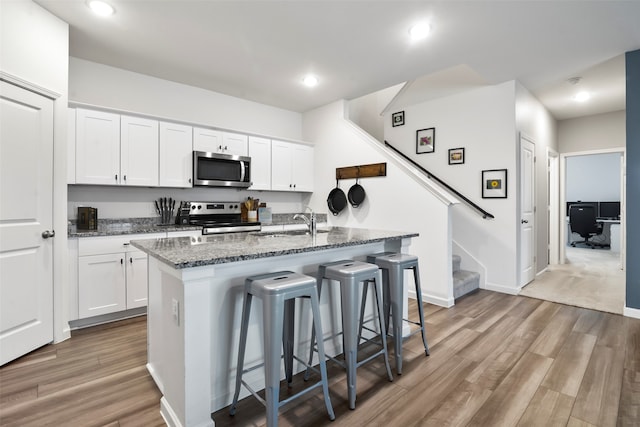 kitchen featuring white cabinetry, a center island with sink, and appliances with stainless steel finishes