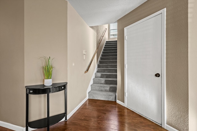 stairway with wood-type flooring and a textured ceiling