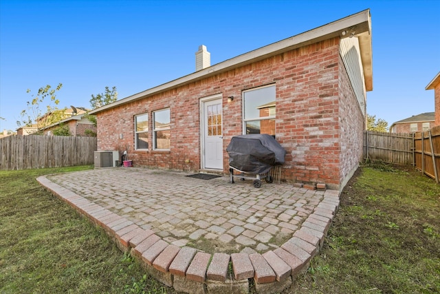 back of property featuring central AC unit, a patio area, and a lawn