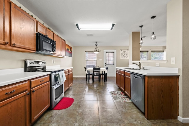 kitchen with appliances with stainless steel finishes, a healthy amount of sunlight, pendant lighting, and sink