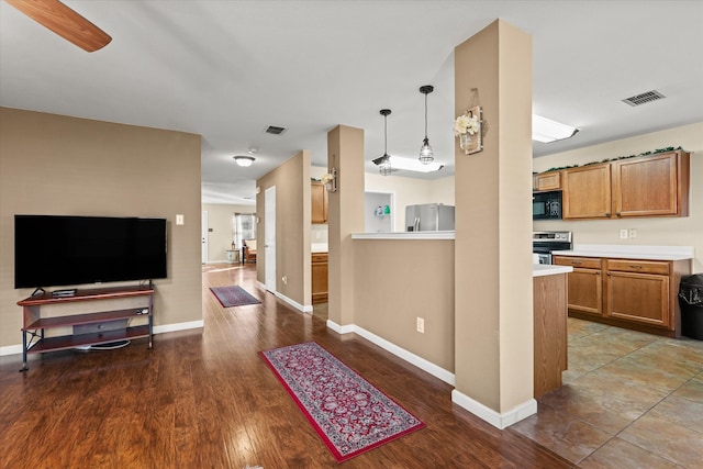 kitchen featuring ceiling fan, stainless steel appliances, hanging light fixtures, and dark hardwood / wood-style floors