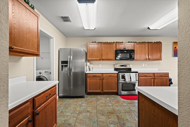 kitchen with a textured ceiling, stainless steel appliances, and washer / clothes dryer