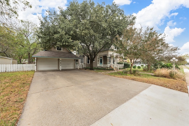 view of property hidden behind natural elements with a garage and a porch