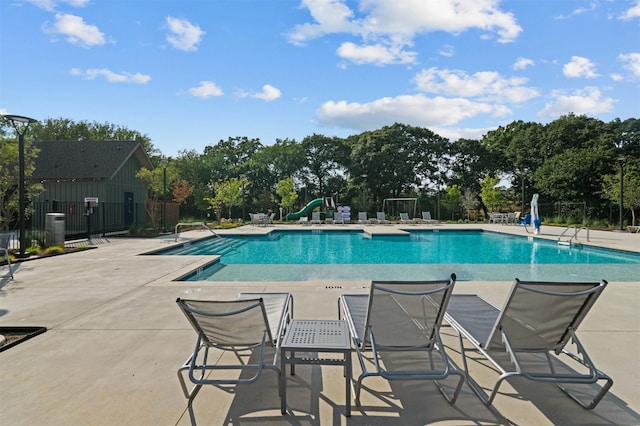 view of swimming pool with a patio area and a water slide