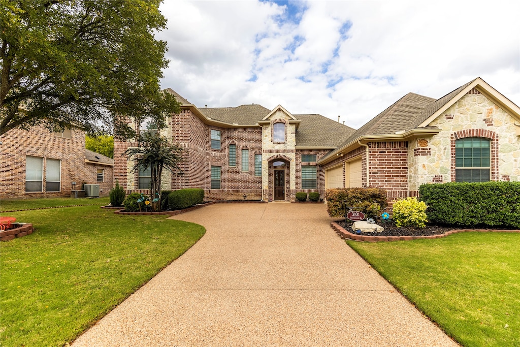 view of front of house featuring central air condition unit, a garage, and a front lawn