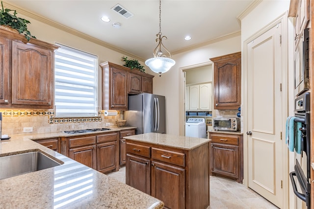 kitchen with appliances with stainless steel finishes, hanging light fixtures, a center island, and backsplash