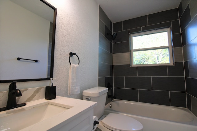 full bathroom featuring tiled shower / bath, vanity, and toilet