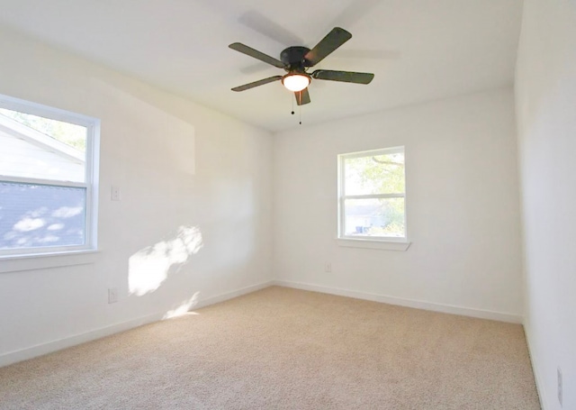 carpeted spare room featuring ceiling fan and a wealth of natural light