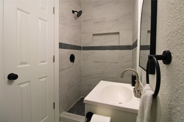 bathroom with a tile shower and vanity