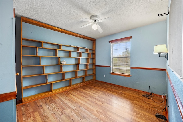 spare room with a textured ceiling, ceiling fan, and light hardwood / wood-style flooring