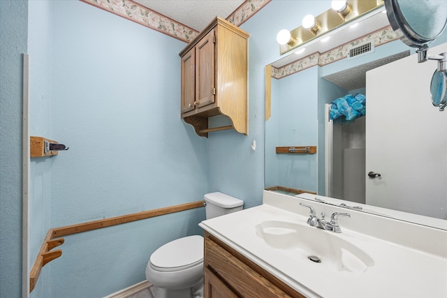 bathroom featuring vanity, a textured ceiling, and toilet