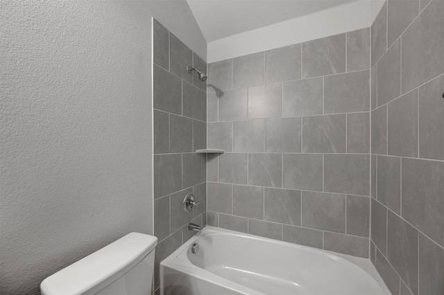 bathroom featuring toilet, tiled shower / bath combo, and lofted ceiling