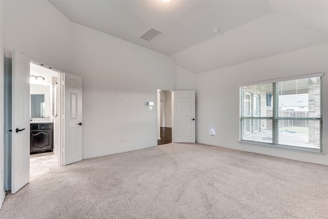 unfurnished bedroom with ensuite bath, lofted ceiling, and carpet floors