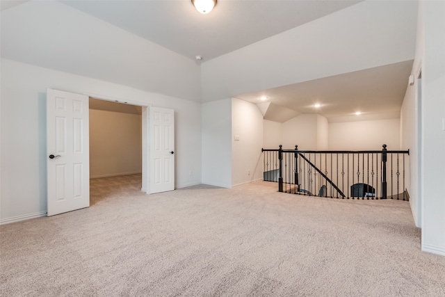 spare room featuring vaulted ceiling and light carpet