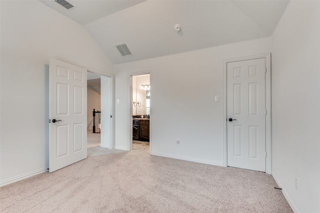 unfurnished bedroom with lofted ceiling, light colored carpet, and connected bathroom