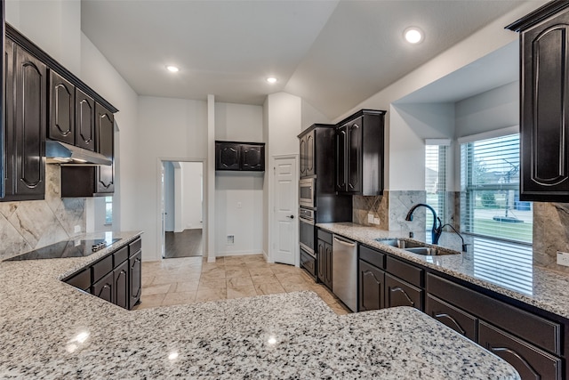 kitchen with stainless steel appliances, light stone countertops, sink, and decorative backsplash