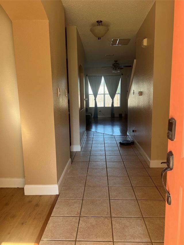 hall featuring tile patterned flooring and a textured ceiling