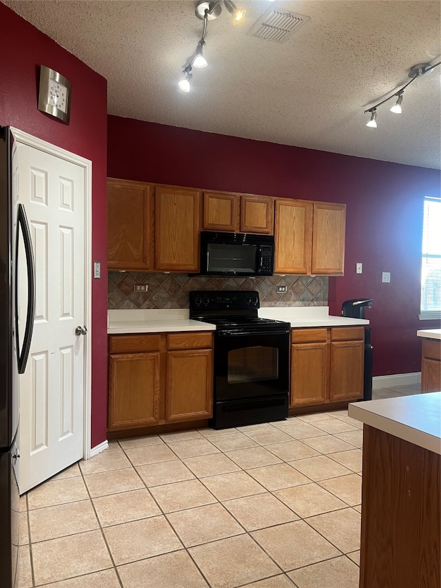 kitchen featuring backsplash, light tile patterned flooring, track lighting, and black appliances