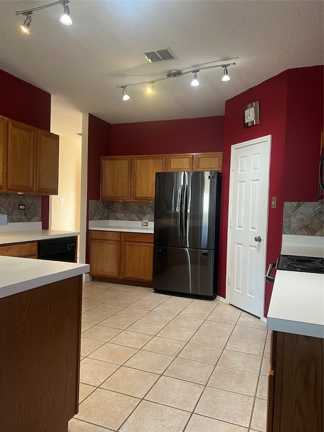 kitchen featuring stainless steel refrigerator, a textured ceiling, light tile patterned floors, and decorative backsplash