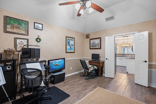 office featuring ceiling fan with notable chandelier, dark hardwood / wood-style flooring, and vaulted ceiling