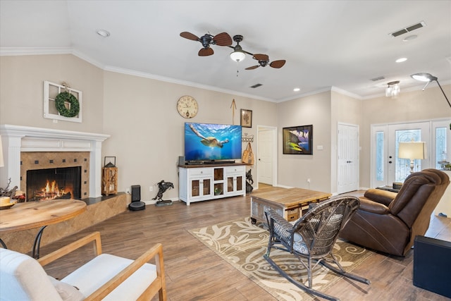 living room featuring a fireplace, hardwood / wood-style flooring, ceiling fan, and crown molding